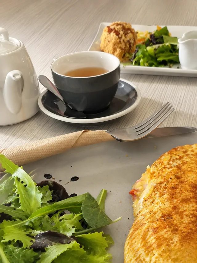 A cup of coffee beside breakfast at a Daydream Café table