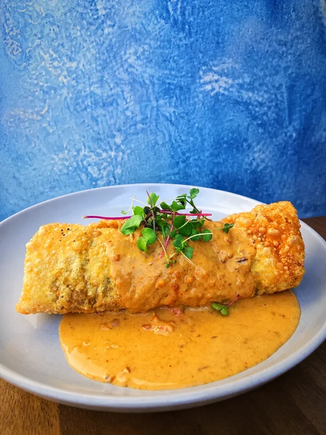 A golden fried roll served with creamy sauce at Daydream Café