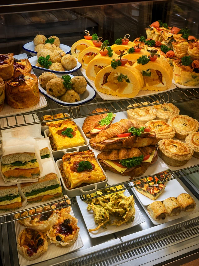 A display cabinet filled with pastries, sandwiches and savoury food