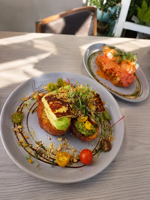 A colourful plate with toast, avocado, salmon and greens